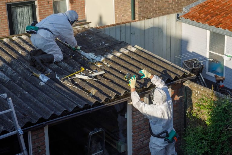 Certified asbestos abatement crew removing hazardous corrugated sheeting from a garage roof