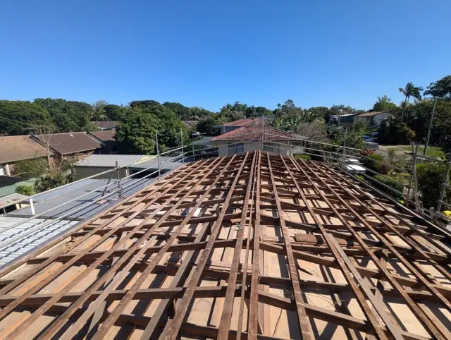 Top-down view of a house under construction showing wooden roof trusses and scaffolding.